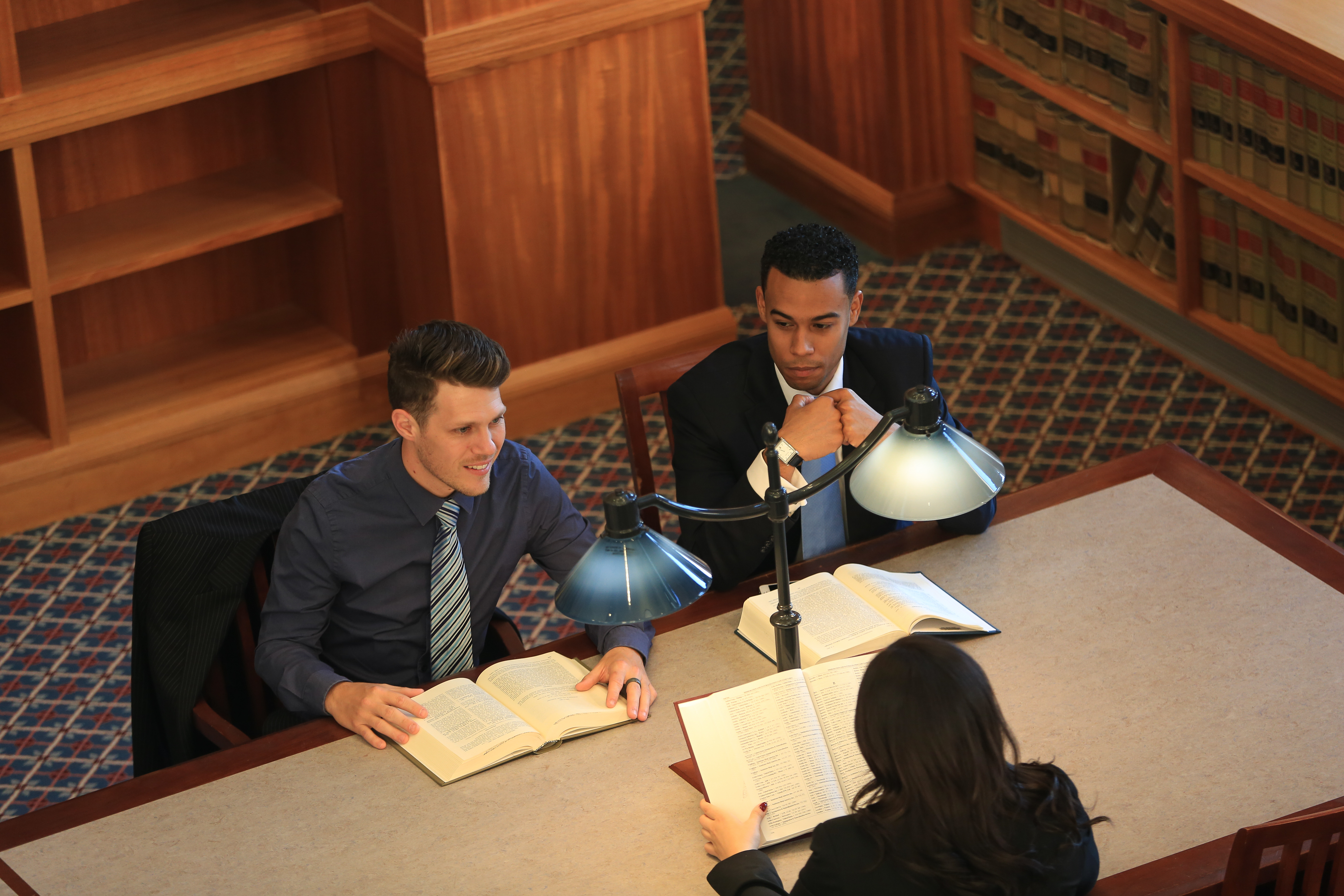 two professionals sitting around a table and discussing business with papers and a laptop.