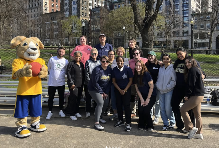 CAS Honors students smiling and posing with Rammy on a basketball court