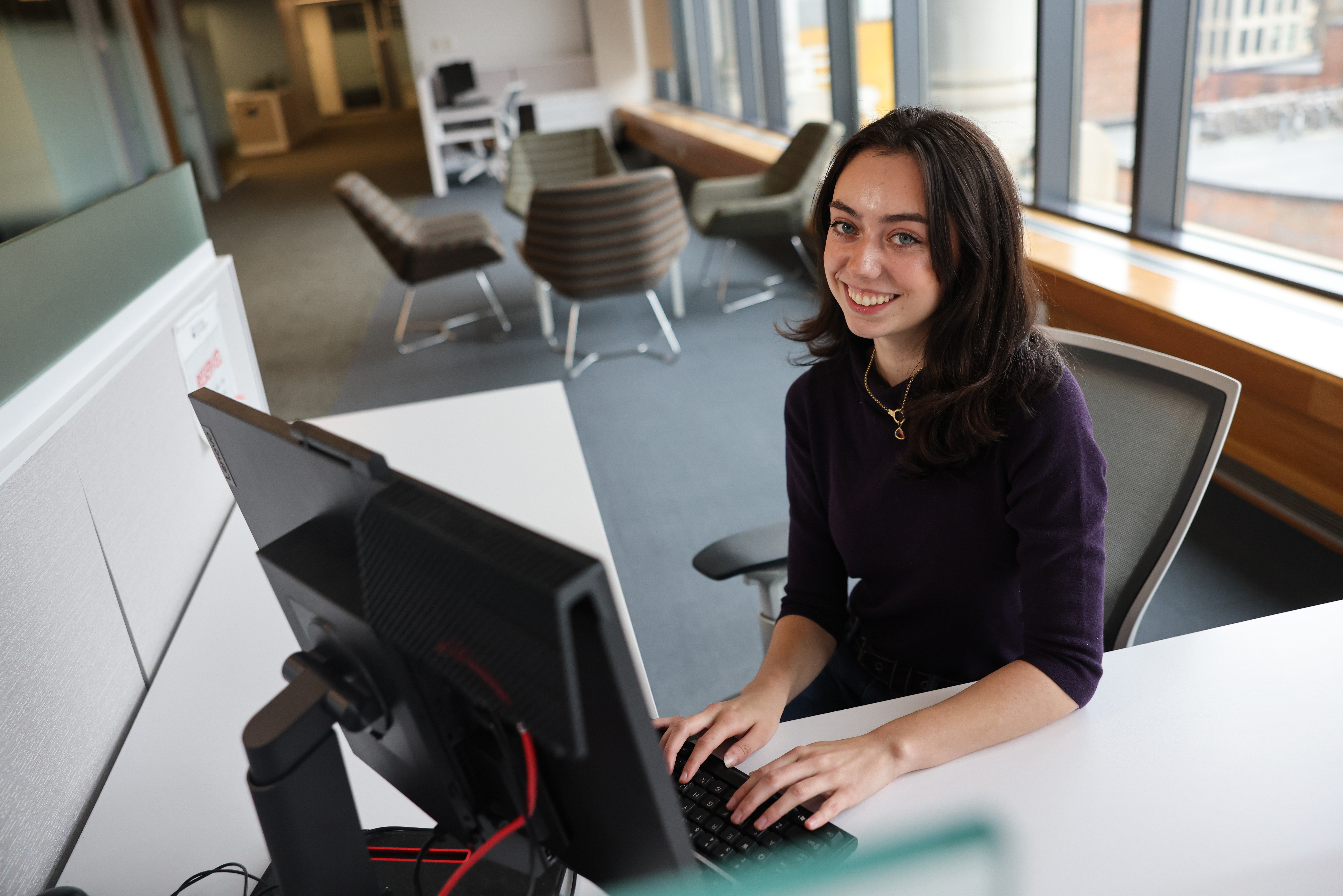 Young white professional woman typing at a computer and similing