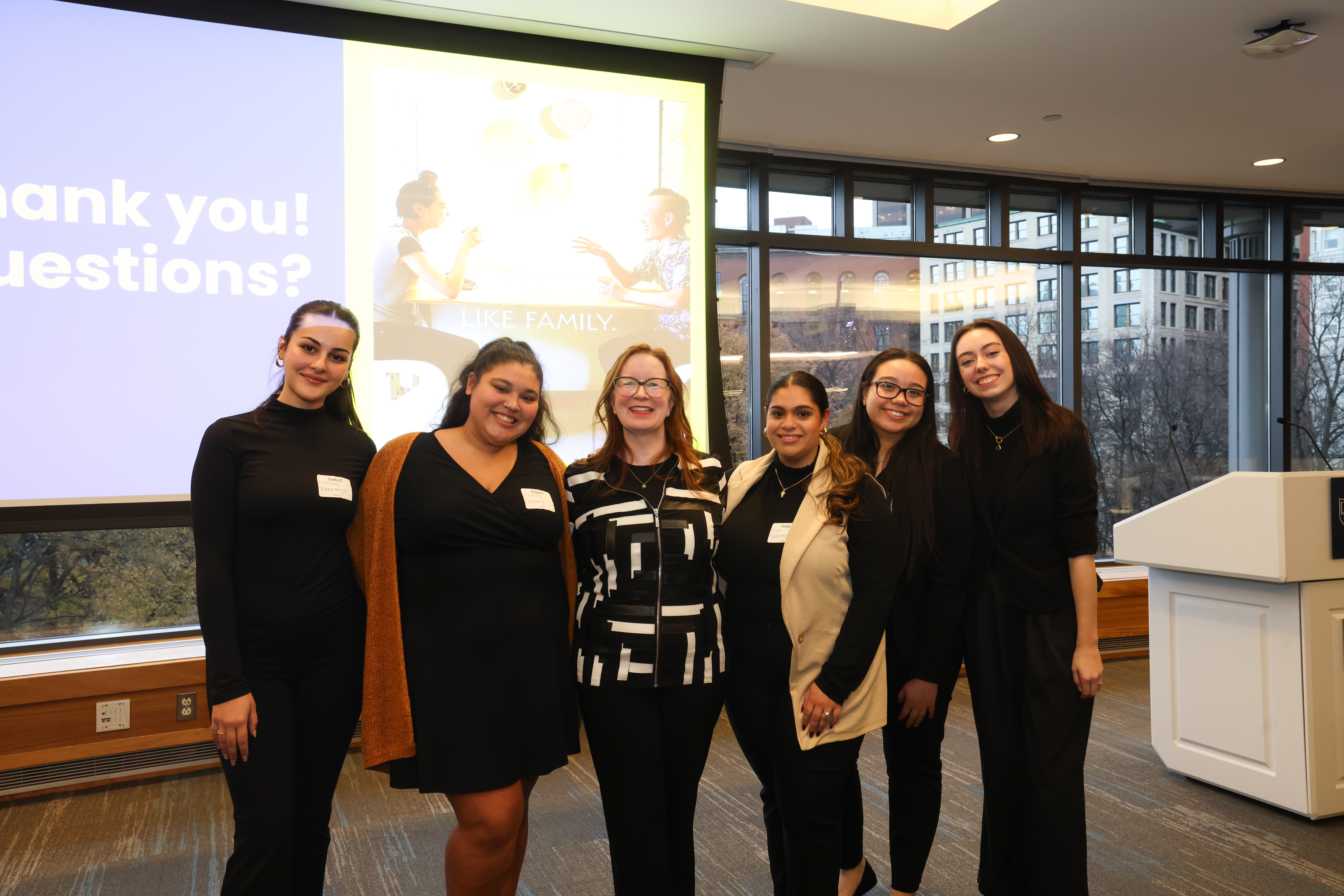 Group of women smiling in front of a screen