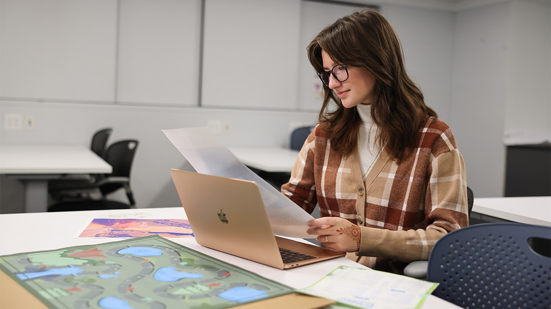 two professionals sitting around a table and discussing business with papers and a laptop.