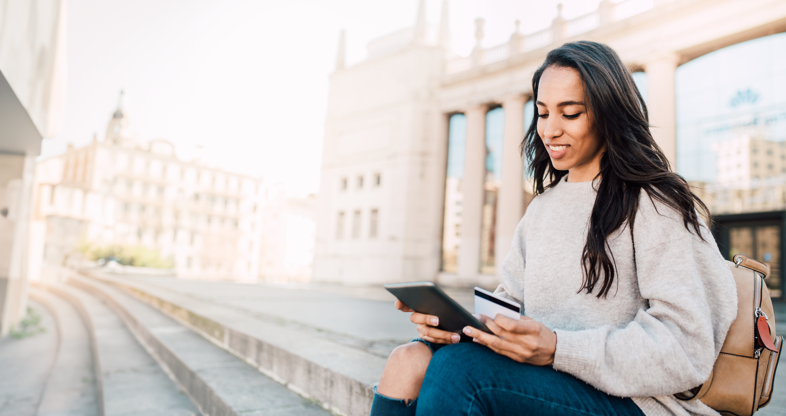 Woman looking at tablet while holding a card