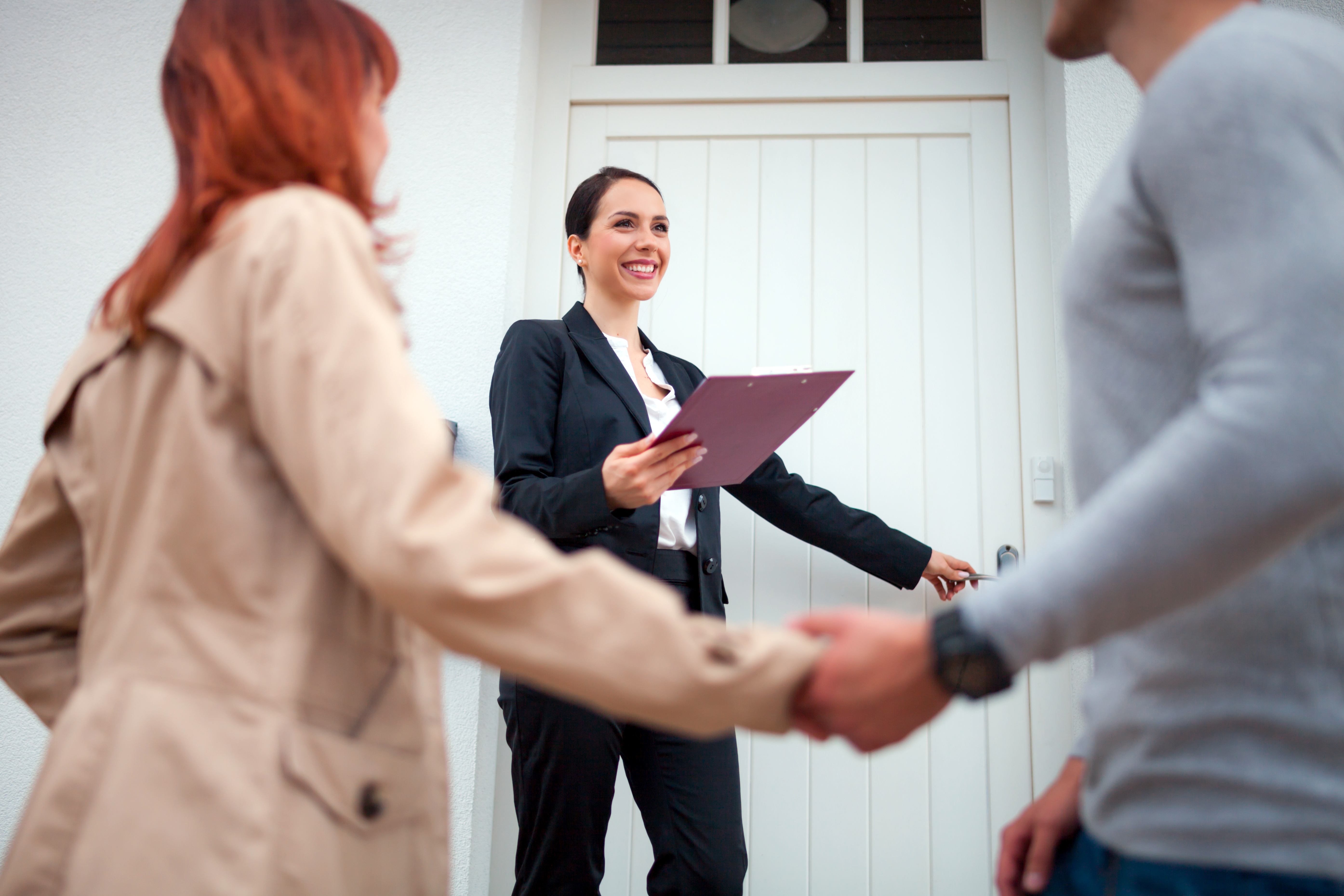 Woman realtor smiling in front of a house