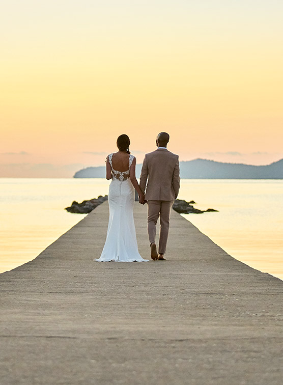 A couple on their wedding day walking into the sunset.
