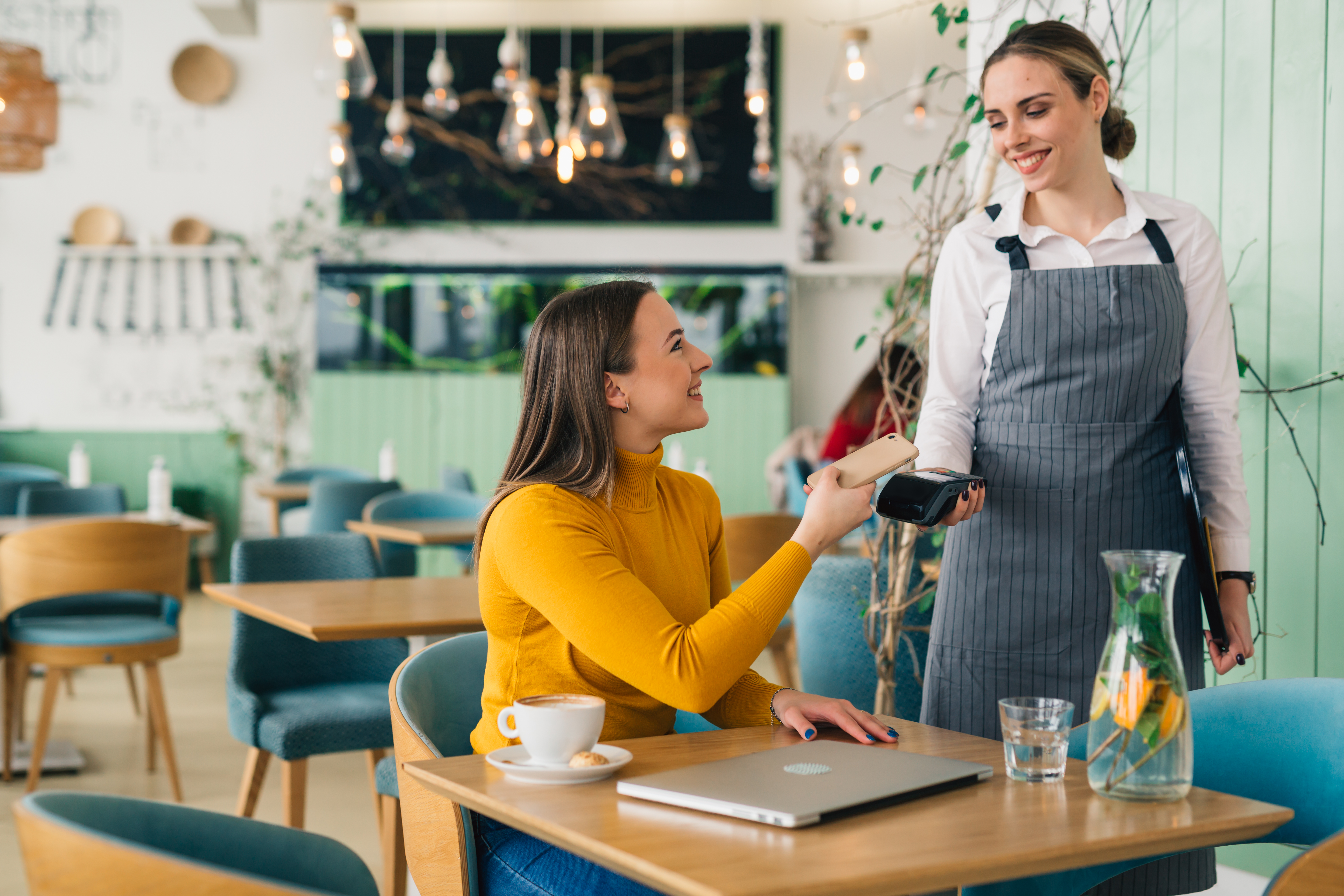 woman paying c contactless with smartphone in cafe