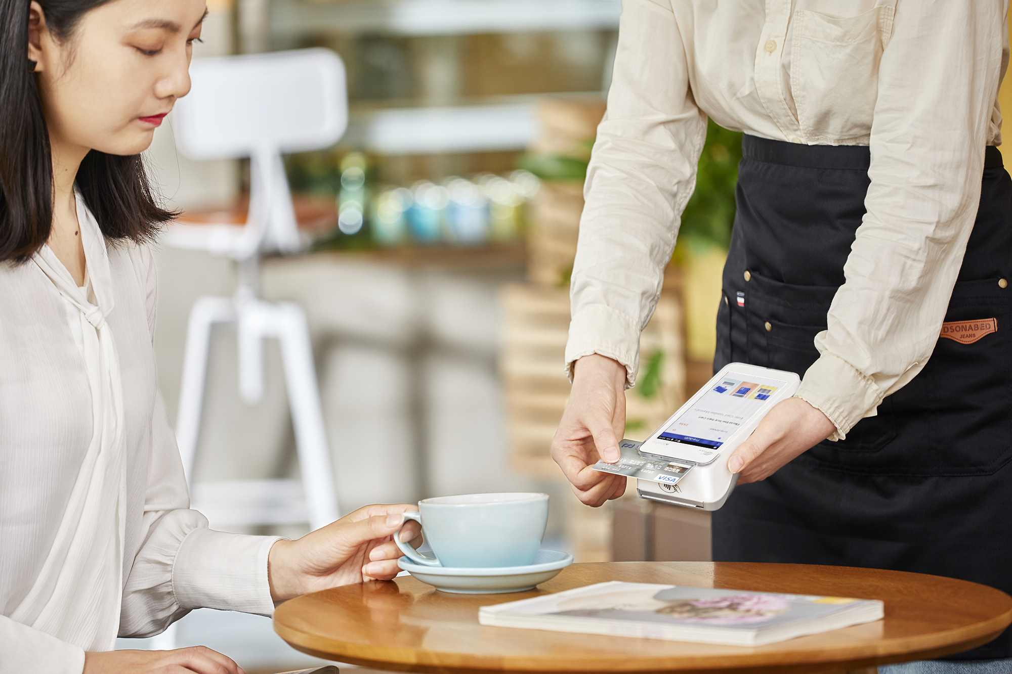 server at restaurant holding acceptance terminal and swiping card at table