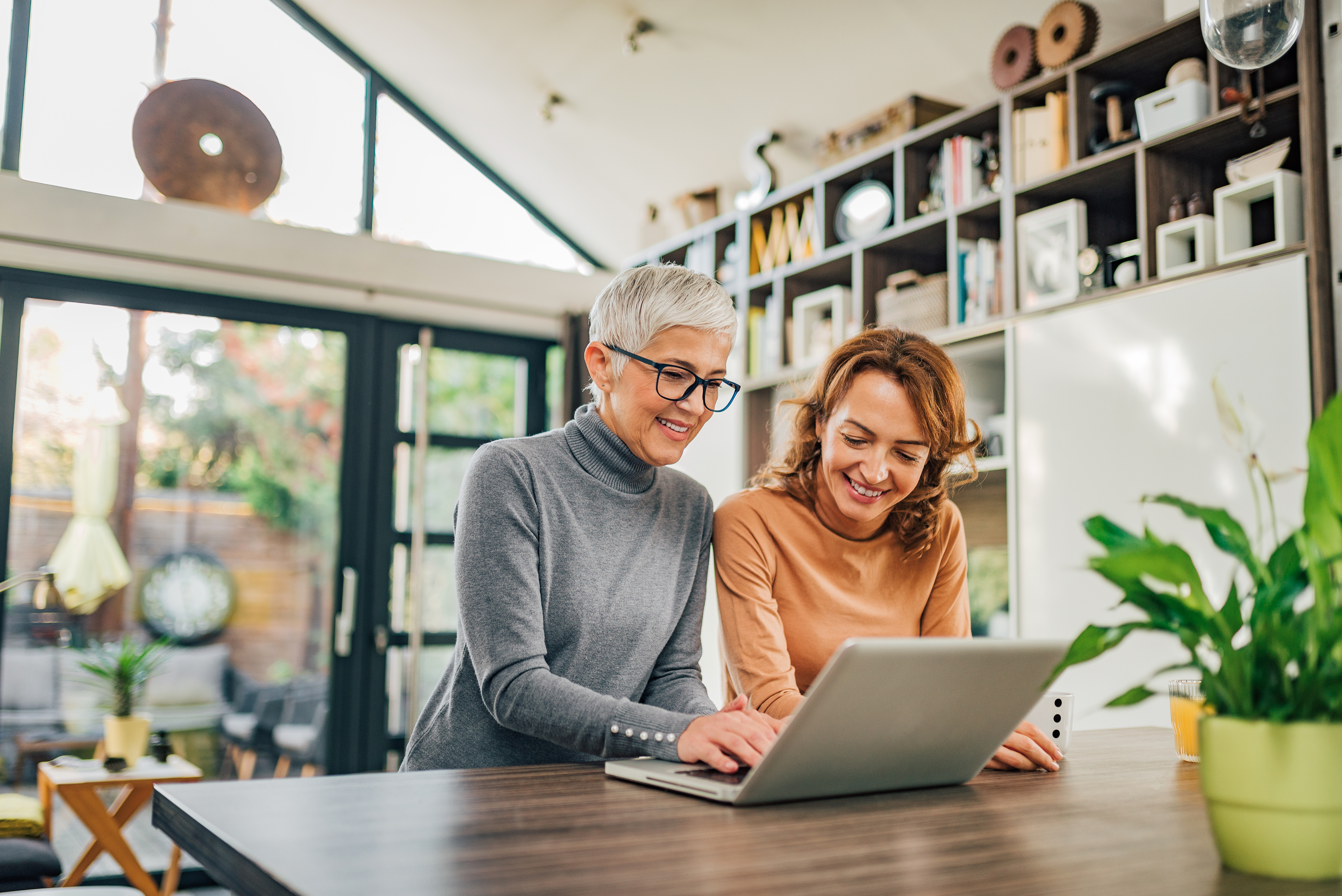 Portrait of a two women of a different age using laptop in modern house.