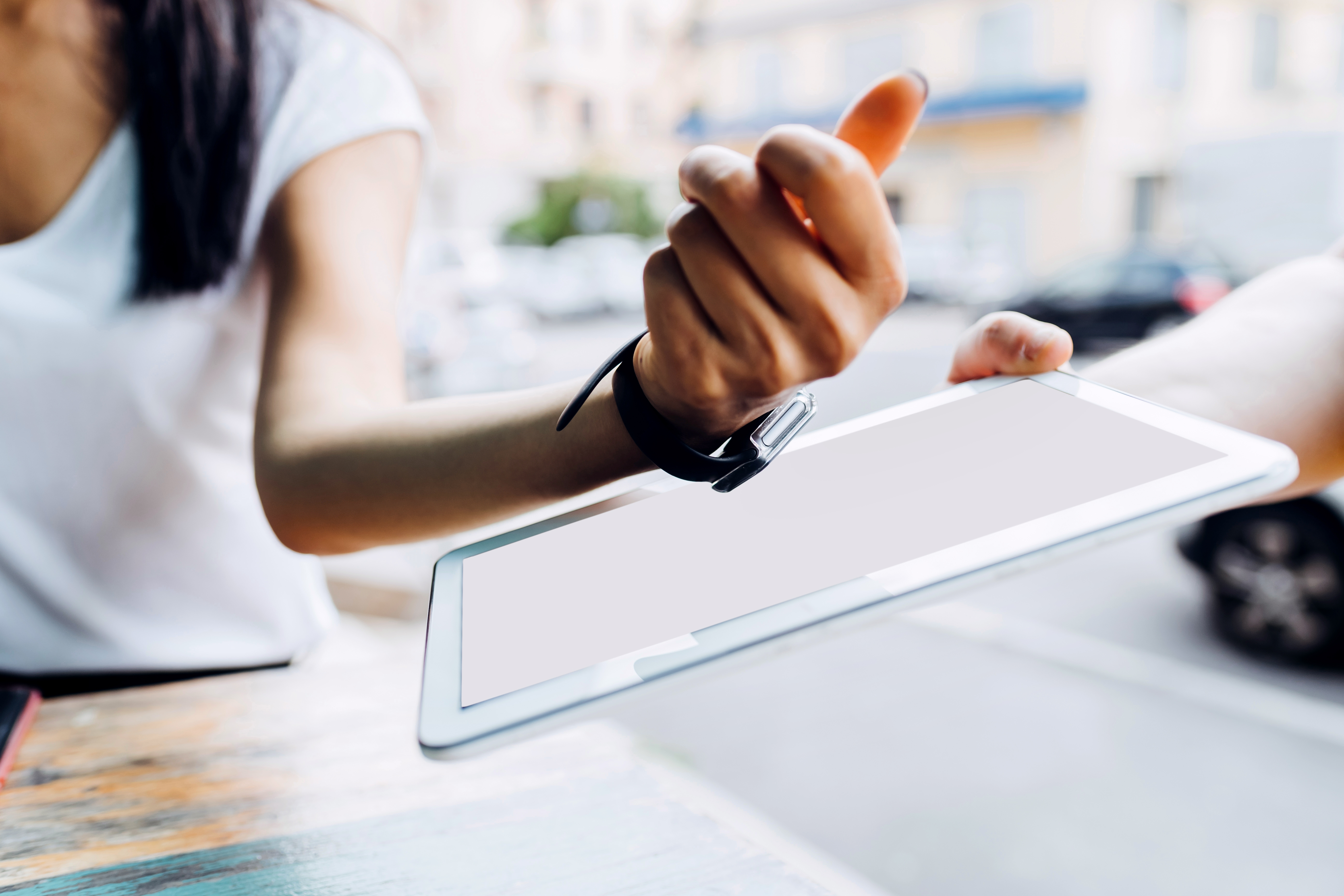 women's arm tapping her smart watch onto tablet to pay