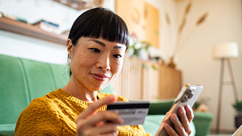 millennial walk on urban street with both hands on phone and smiling
