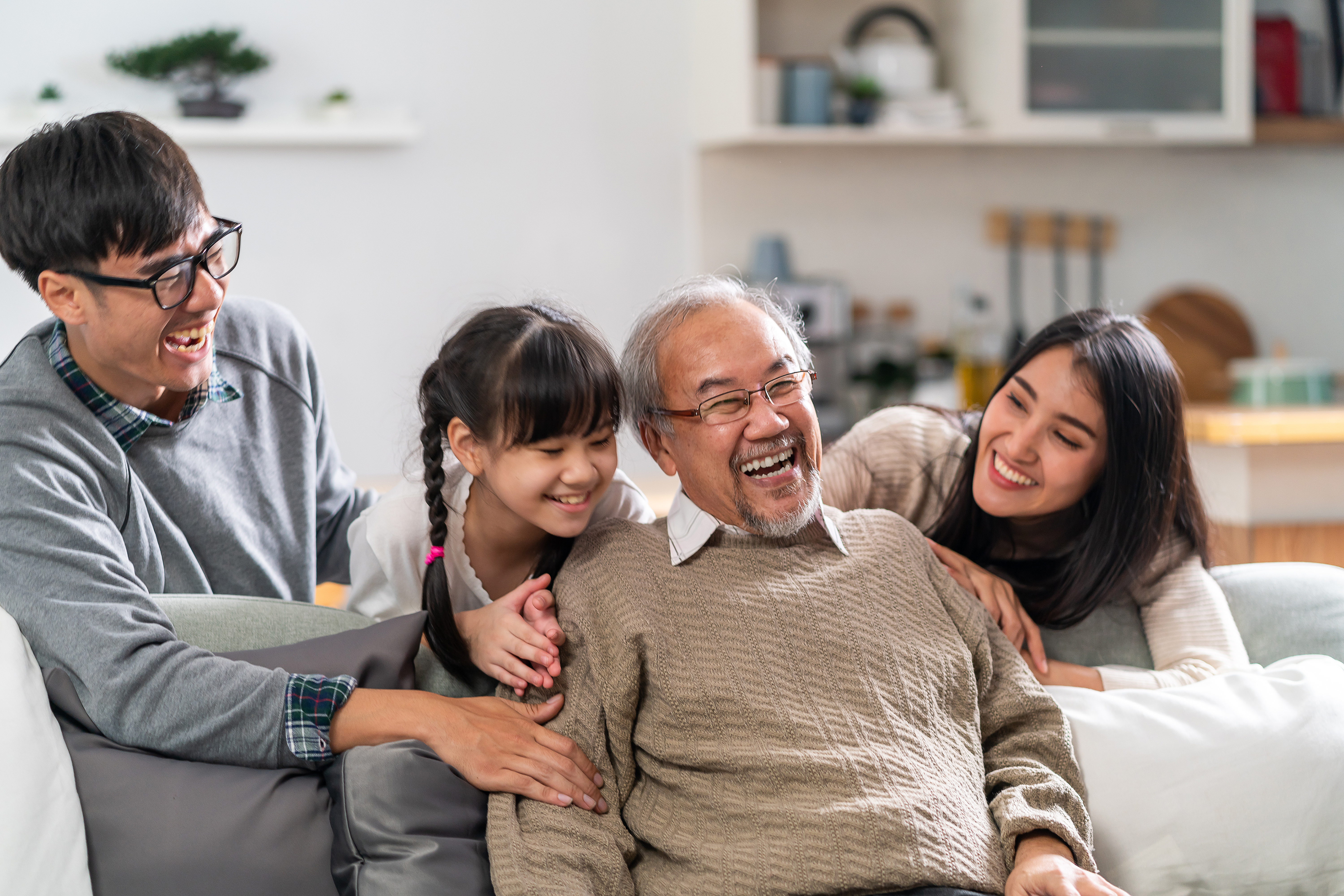 Close up of two Asian woman embracing their grandfather looking happy and laughing