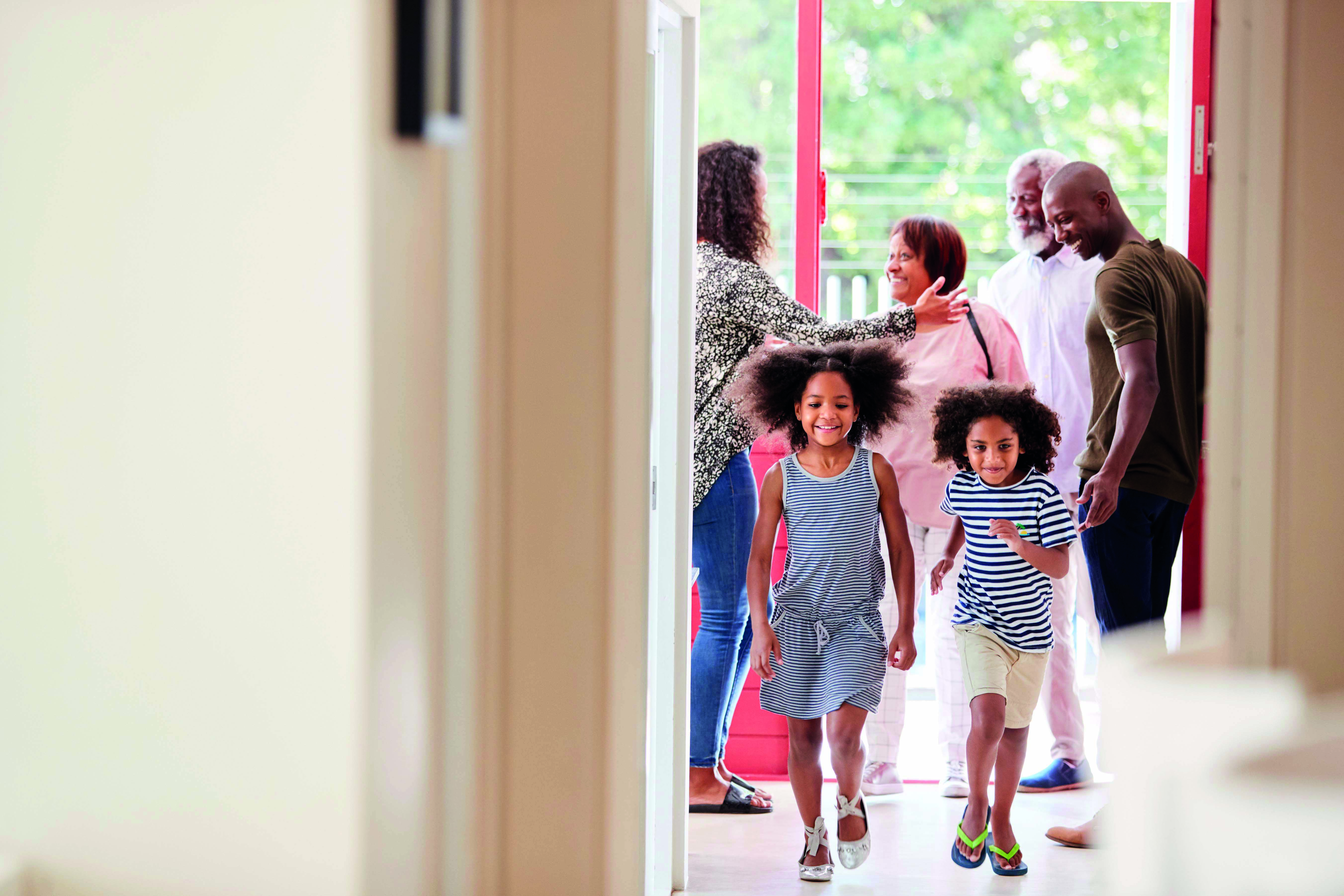 A family joyfully walks together into their home, creating a warm and welcoming atmosphere