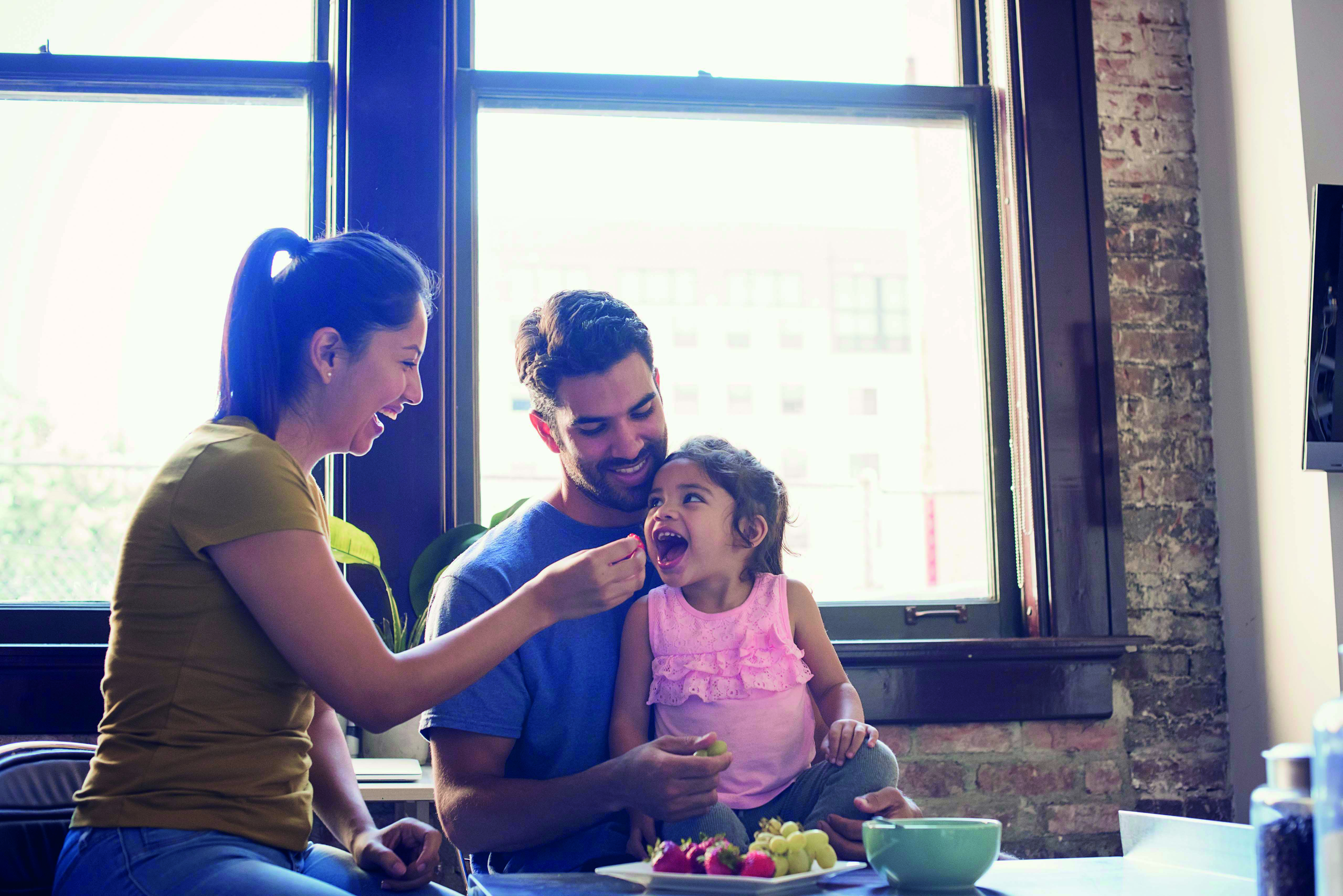 A couple sharing fruit with their child, cheerful setting