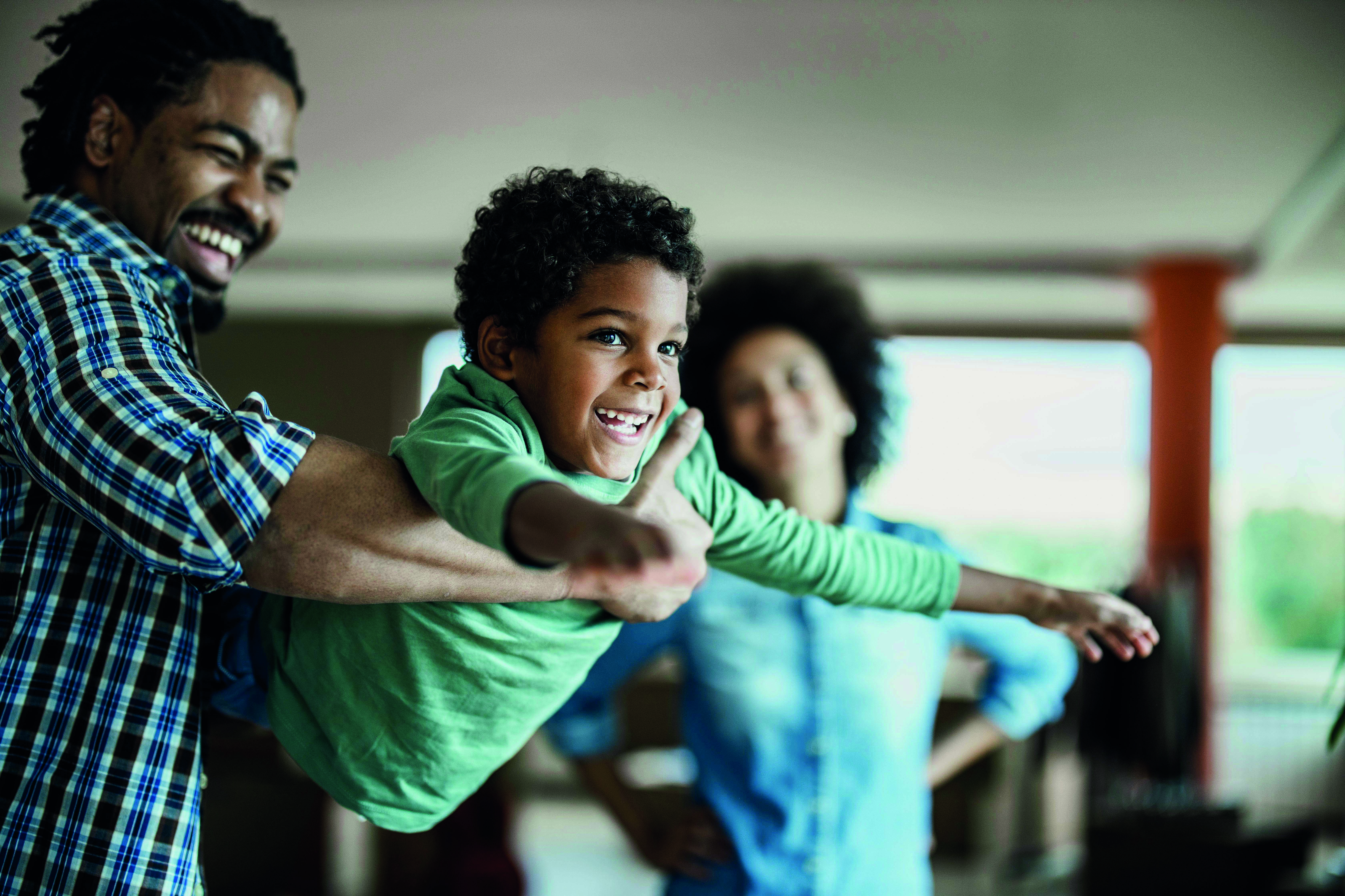 A joyful African American boy playing with his father at home, smiling and enjoying quality time together