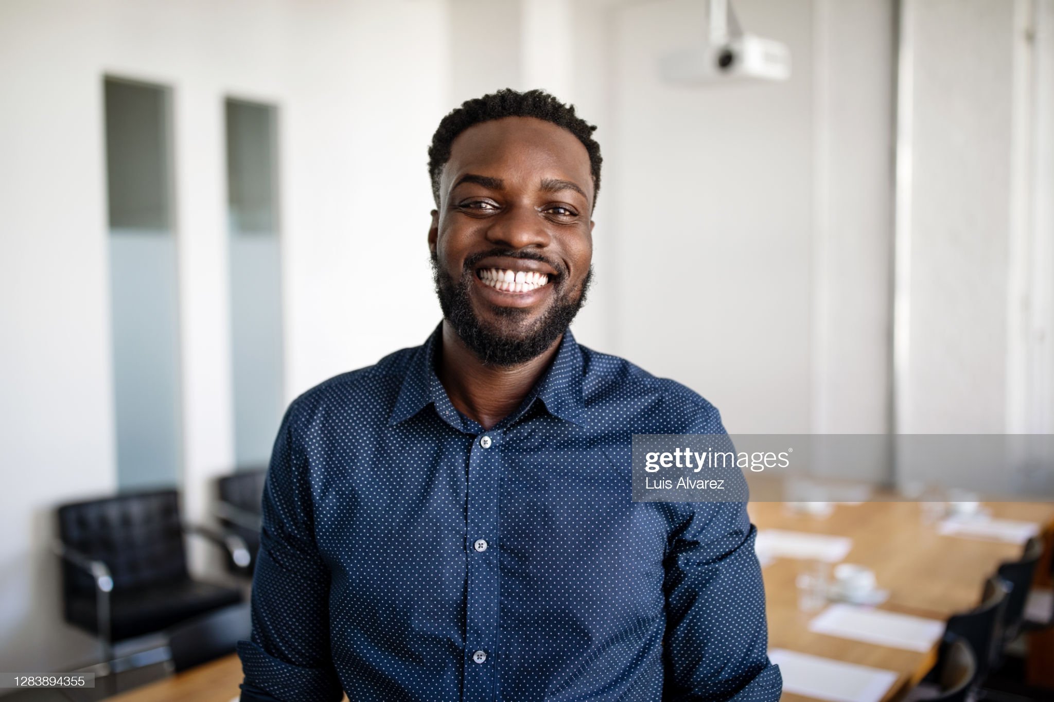 Headshot portrait of smiling young African American businessman in suit pose in own modern office. Profile picture of happy successful male boss or CEO in formalwear show confidence and leadership.