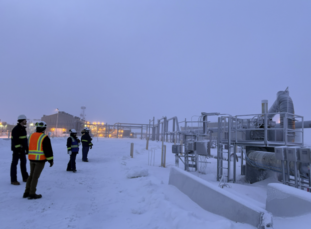 Workers standing next to a structure in the snow.