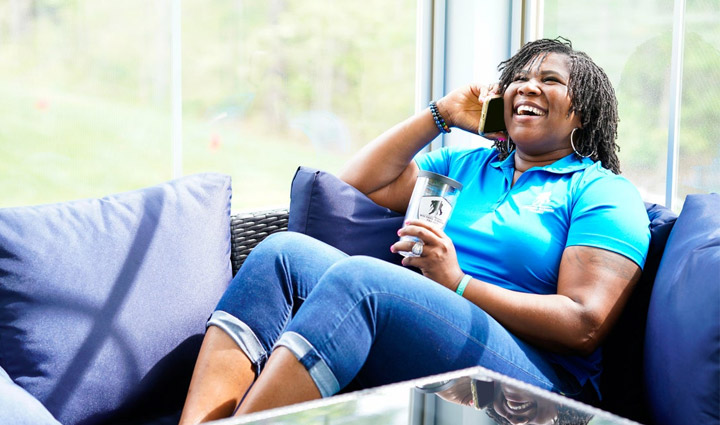 Wounded warrior Taniki Richard sitting on the couch laughing while talking on the phone. 