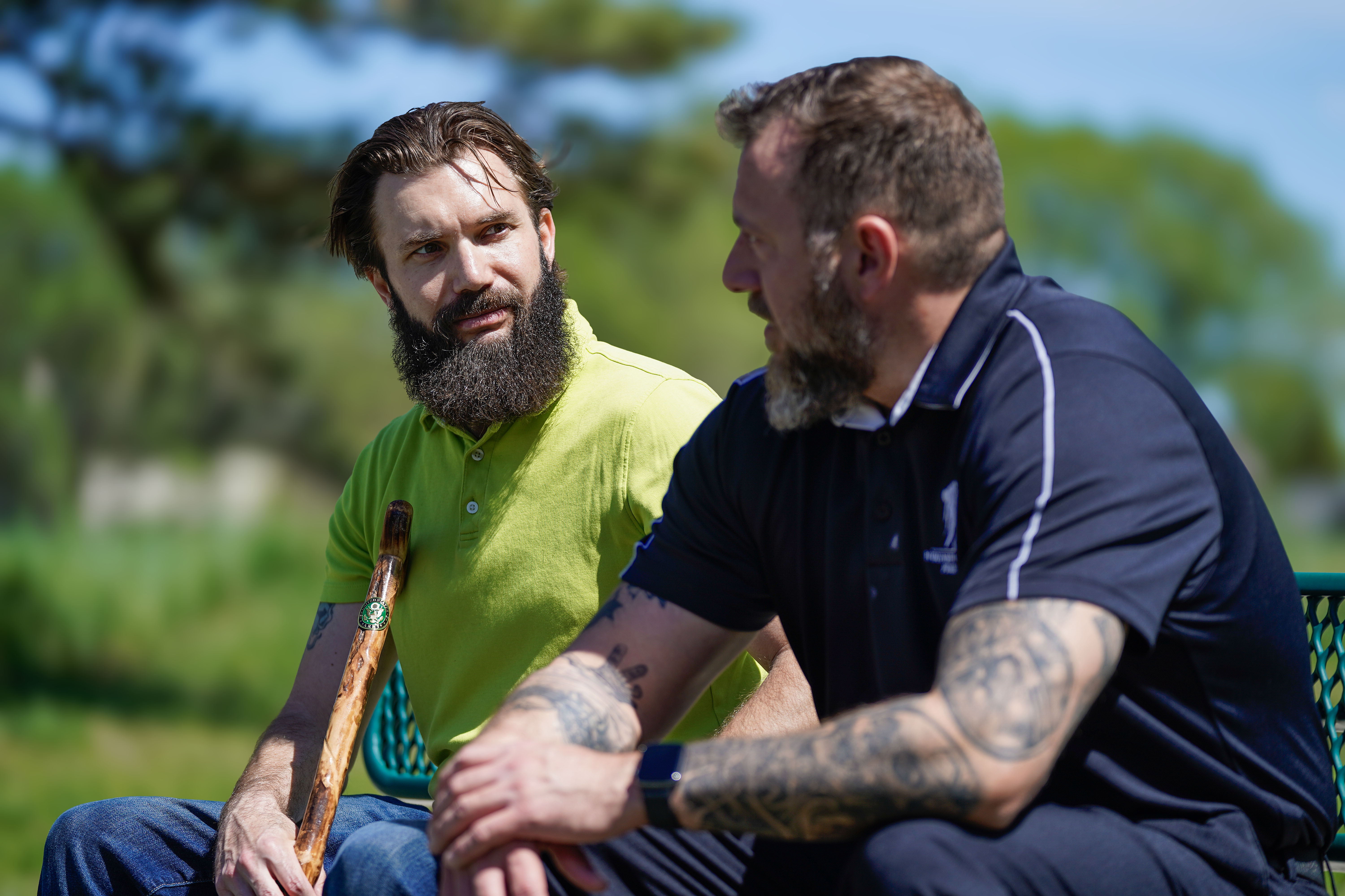 Wounded warriors Drew Carpenter and Anthony Craiden sit on a park bench talking. 