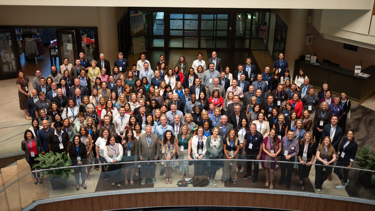 A large group of community partners gathered to take a photo during the 2024 Community Partners & Investments Convening event.