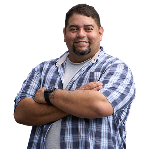 Wounded warrior Tim Aponte smiles with his arms crossed while wearing a short sleeved plaid shirt and a watch on his left wrist.