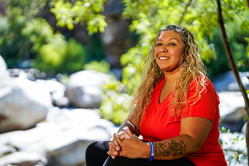 Woman warrior leaning against a tree in the woods