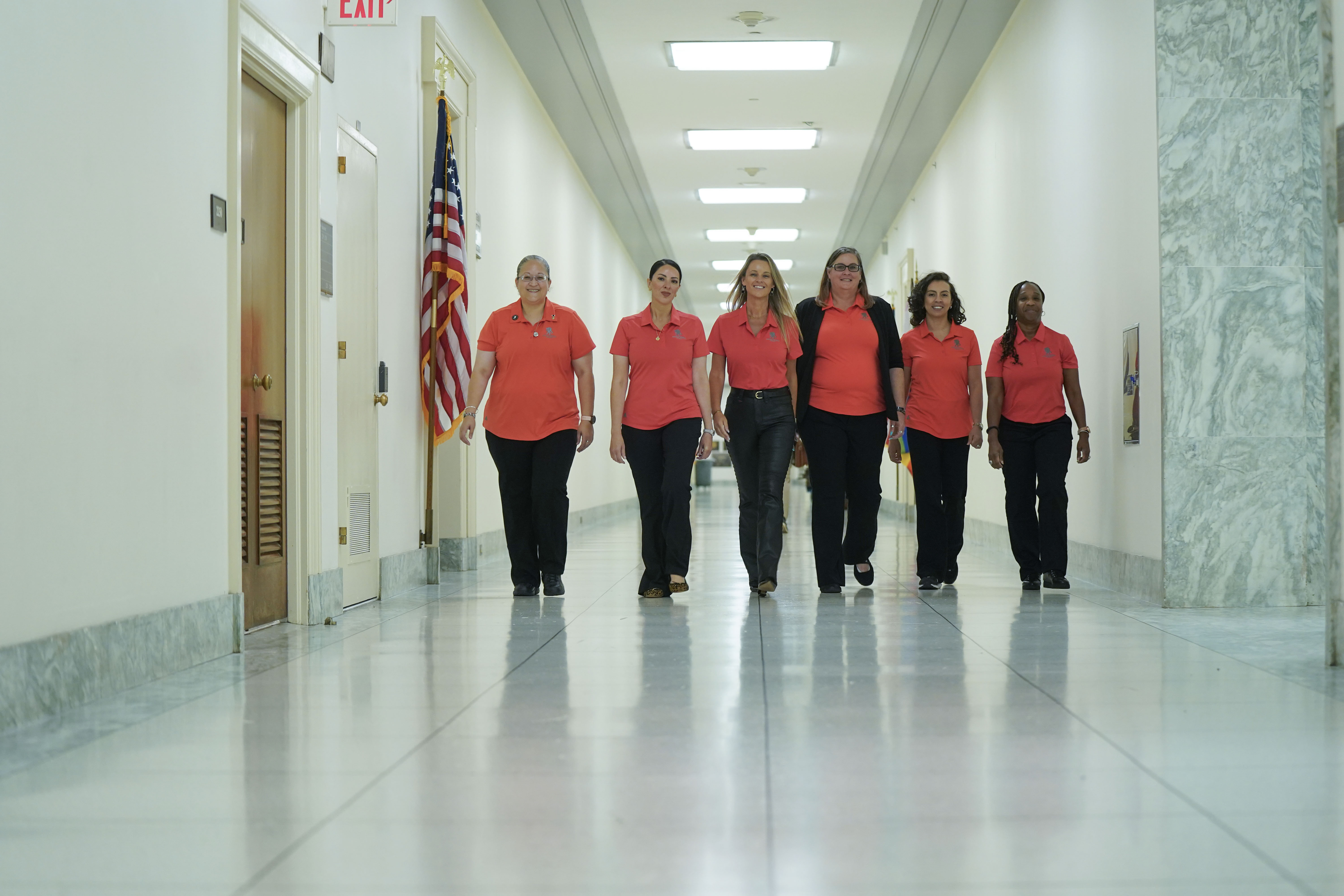 A group of women warriors walk the halls of Congress in matching WWP polo shirts.
