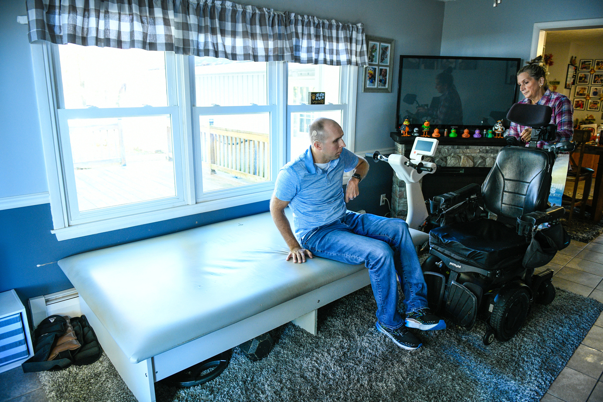 Warrior Josh Sommers transferring from his wheelchair to a physical therapy bed.